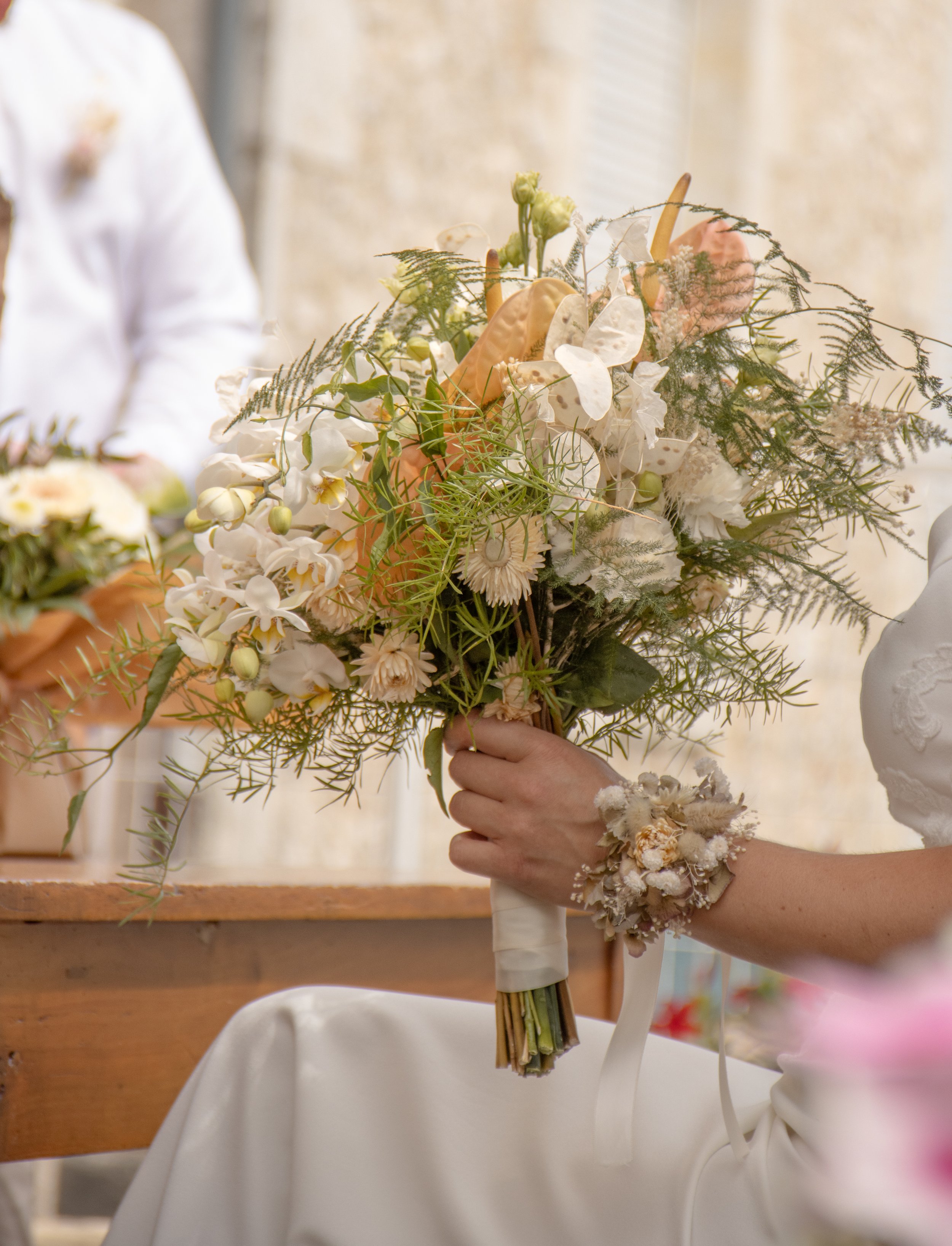 Robe de mariée blanche et bouquet de fleurs blanc, beige et vert.