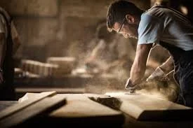 Homme travaillant avec du bois dans un atelier.