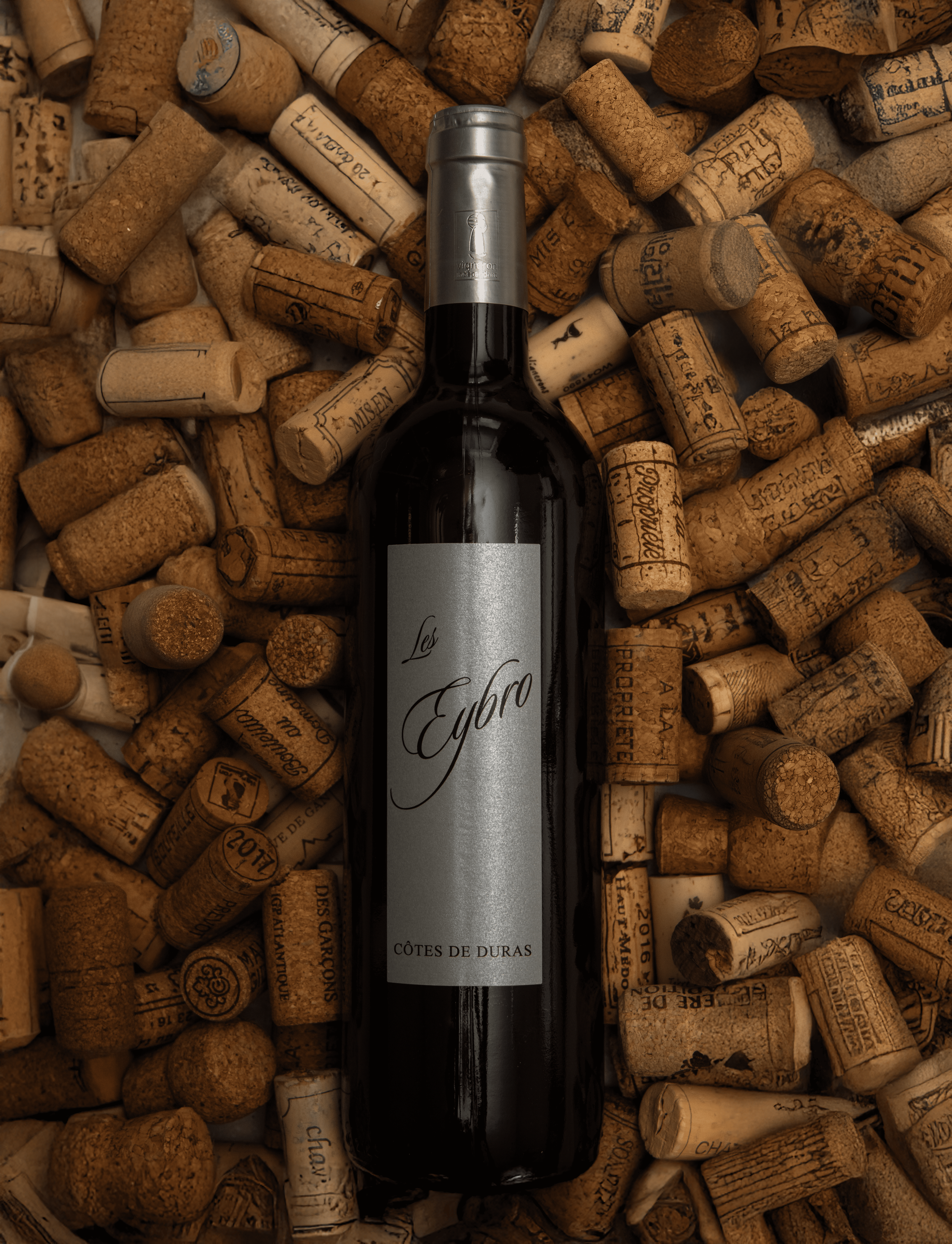 Une bouteille de vin rouge nommée "Les Eybro" entourée de nombreux bouchons de liège.