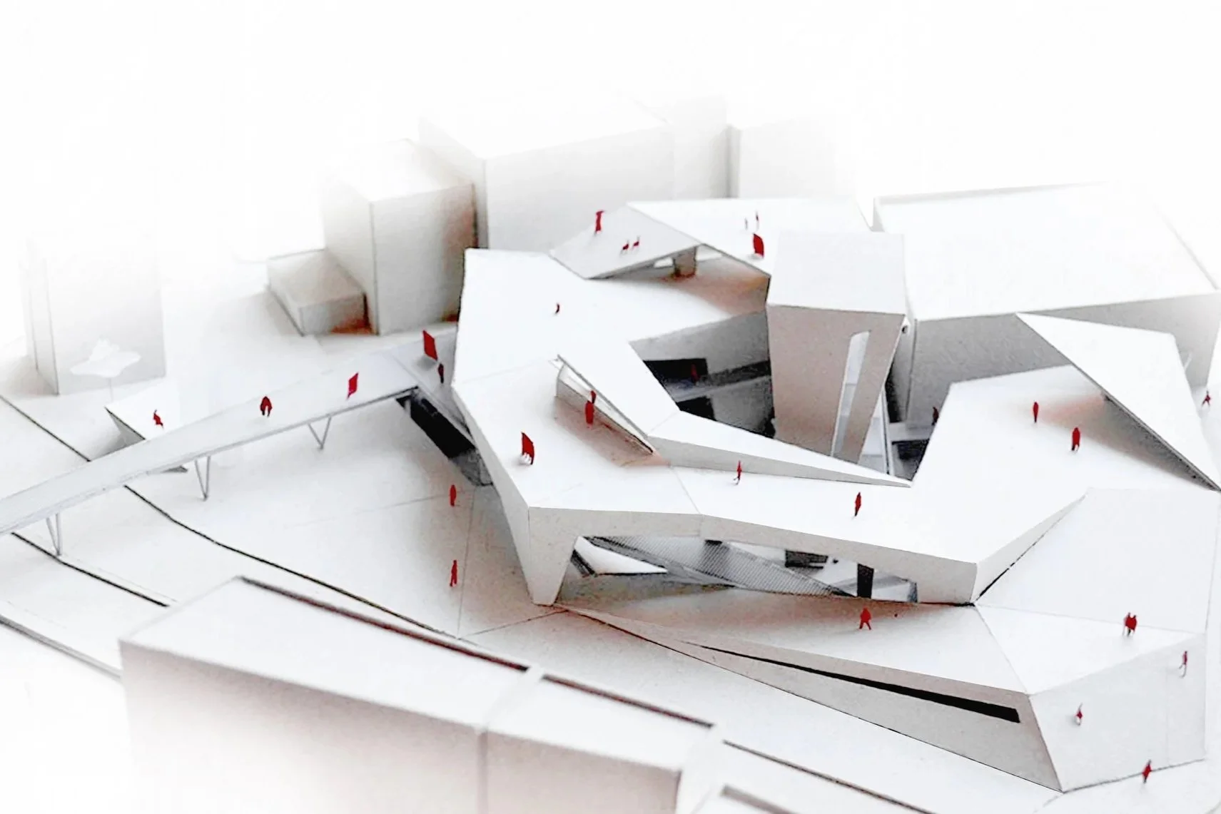 Architectural model of a modern building with white walls and angular design, with small red figures representing people walking around.