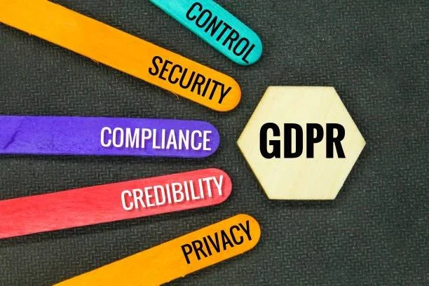 Colorful wooden sticks labeled control, security, compliance, credibility, privacy pointing towards a hexagon with 'GDPR' written on it.