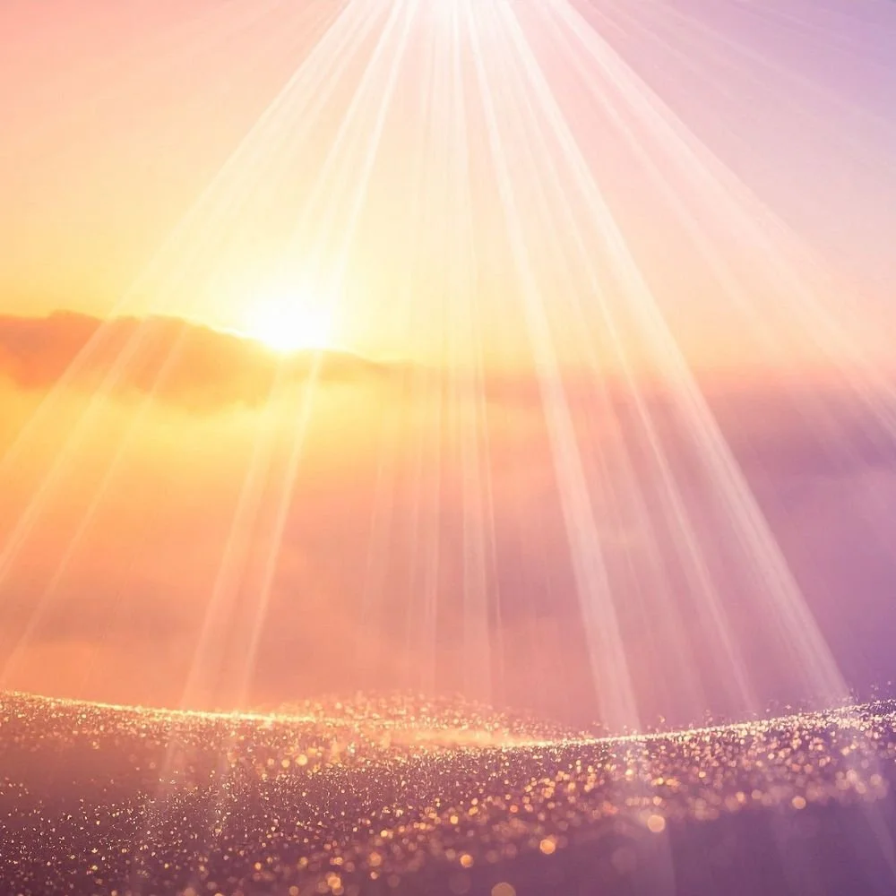 Sonnenstrahlen brechen durch Wolken vor einem Sonnenuntergang über einer goldenen Wasseroberfläche.