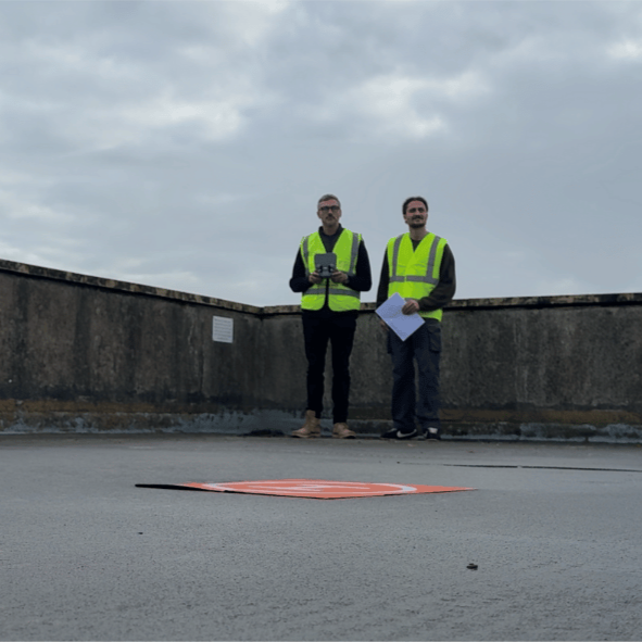 UAV pilot and colleague on a rooftop operating a drone for an Ovrsite roof inspection, supporting safer work at height practice.