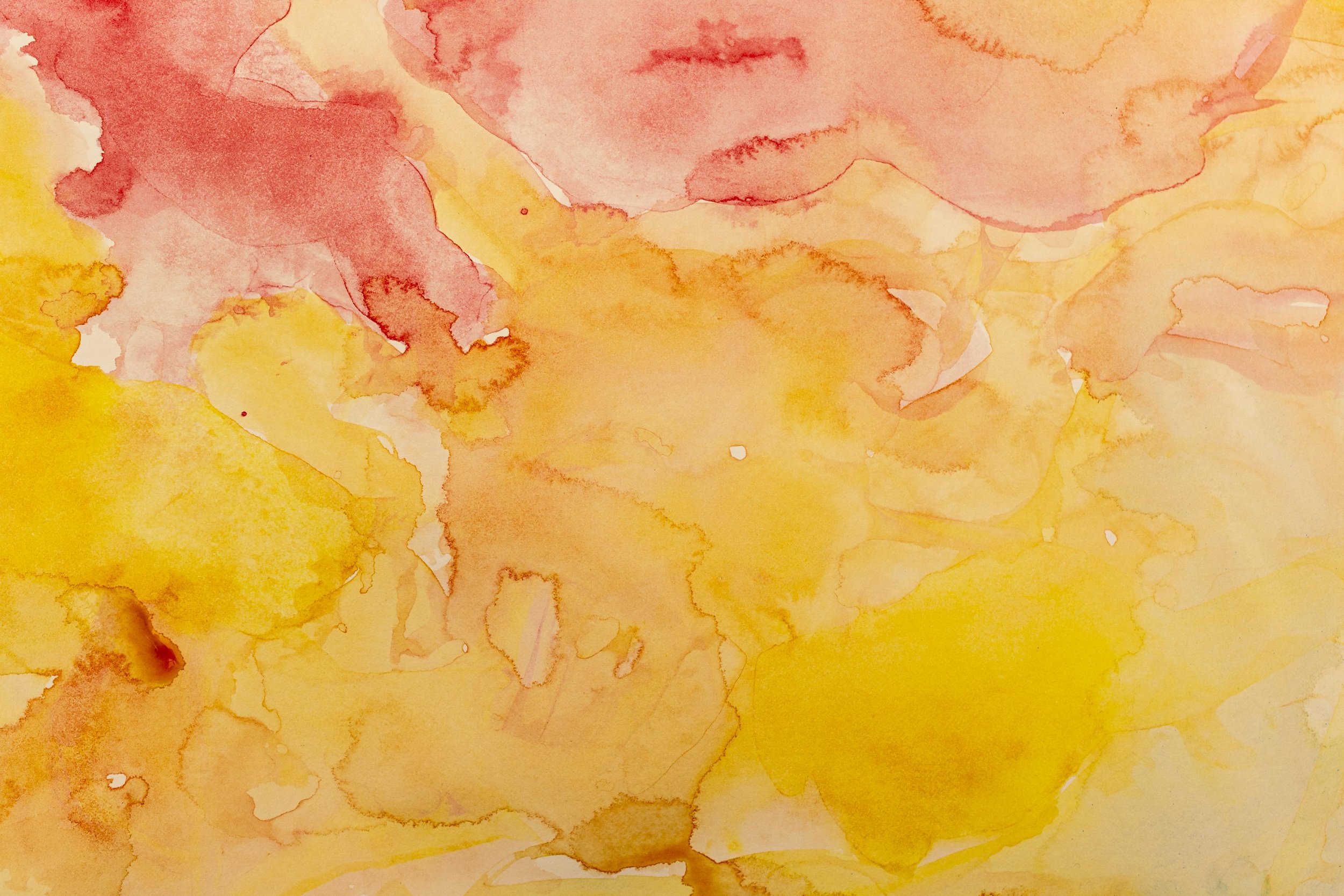 Abstract watercolor background with shades of yellow, orange, and pink blending together.