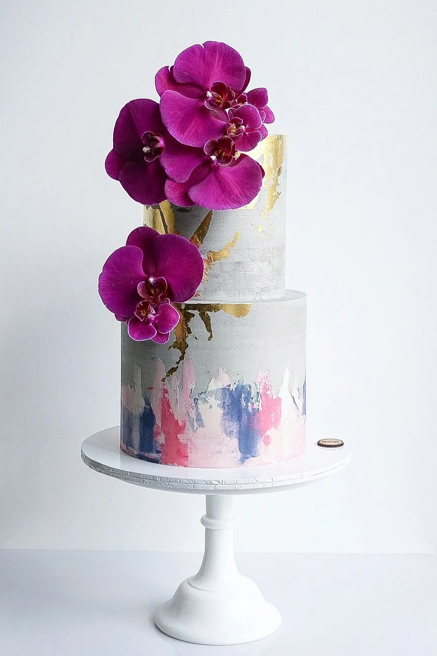 Two-tier buttercream cake with purple orchids and gold details from Buttercream Cake Mastery