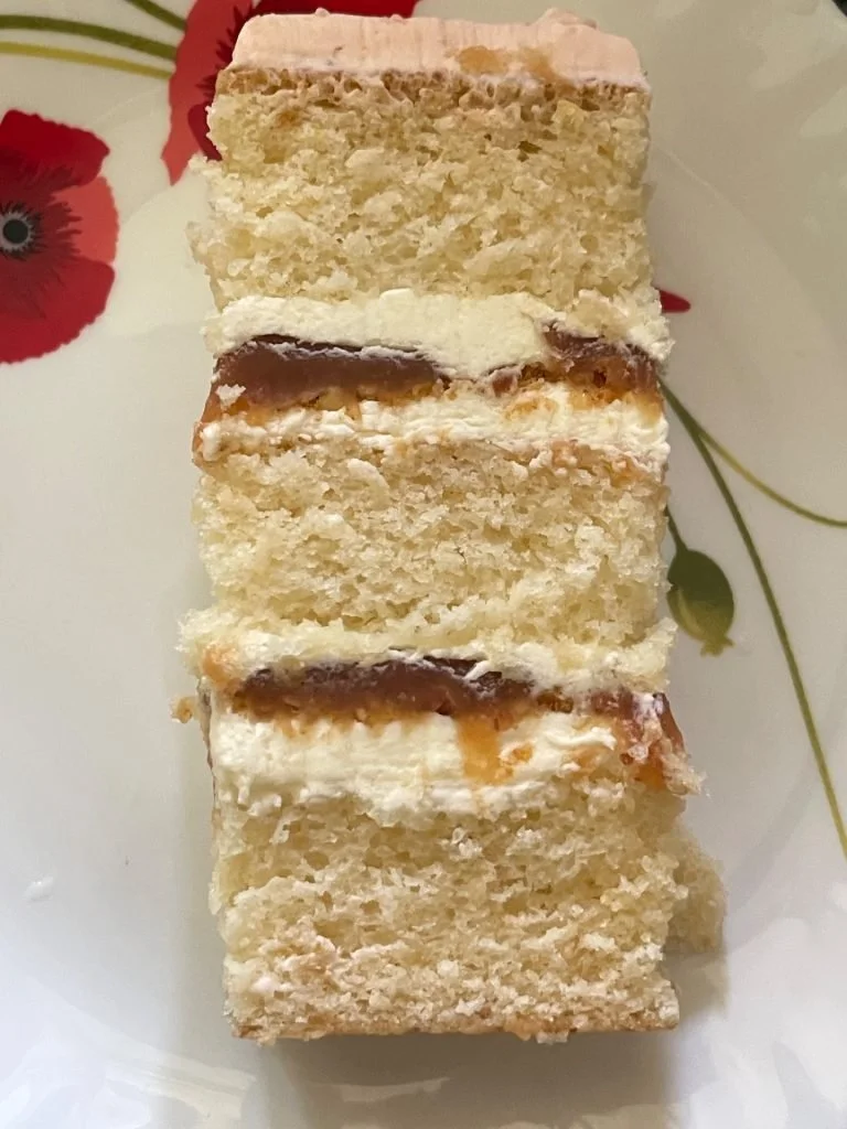 Four slices of layered cake with cream and caramel filling, served on a floral-patterned plate.