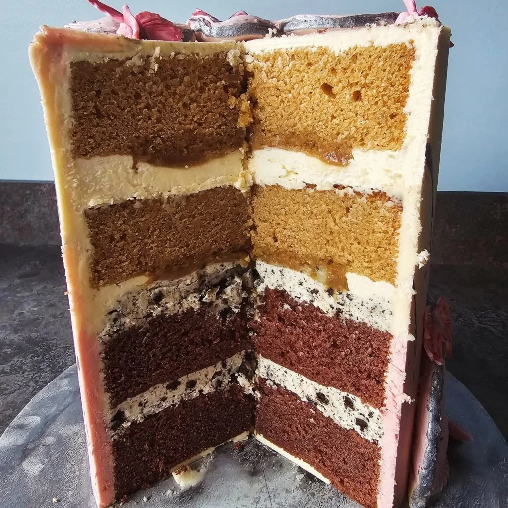 Cross-section of a layered chocolate and vanilla cake with six visible layers, each separated by white frosting, on a cake stand.