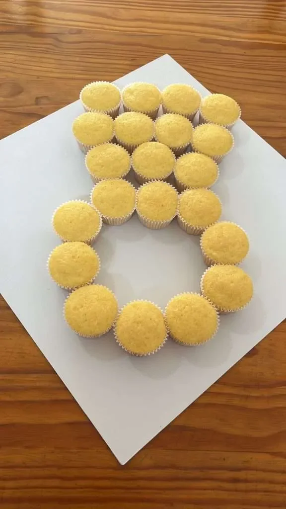 Yellow cupcakes arranged on a white surface to form the shape of the letter A.