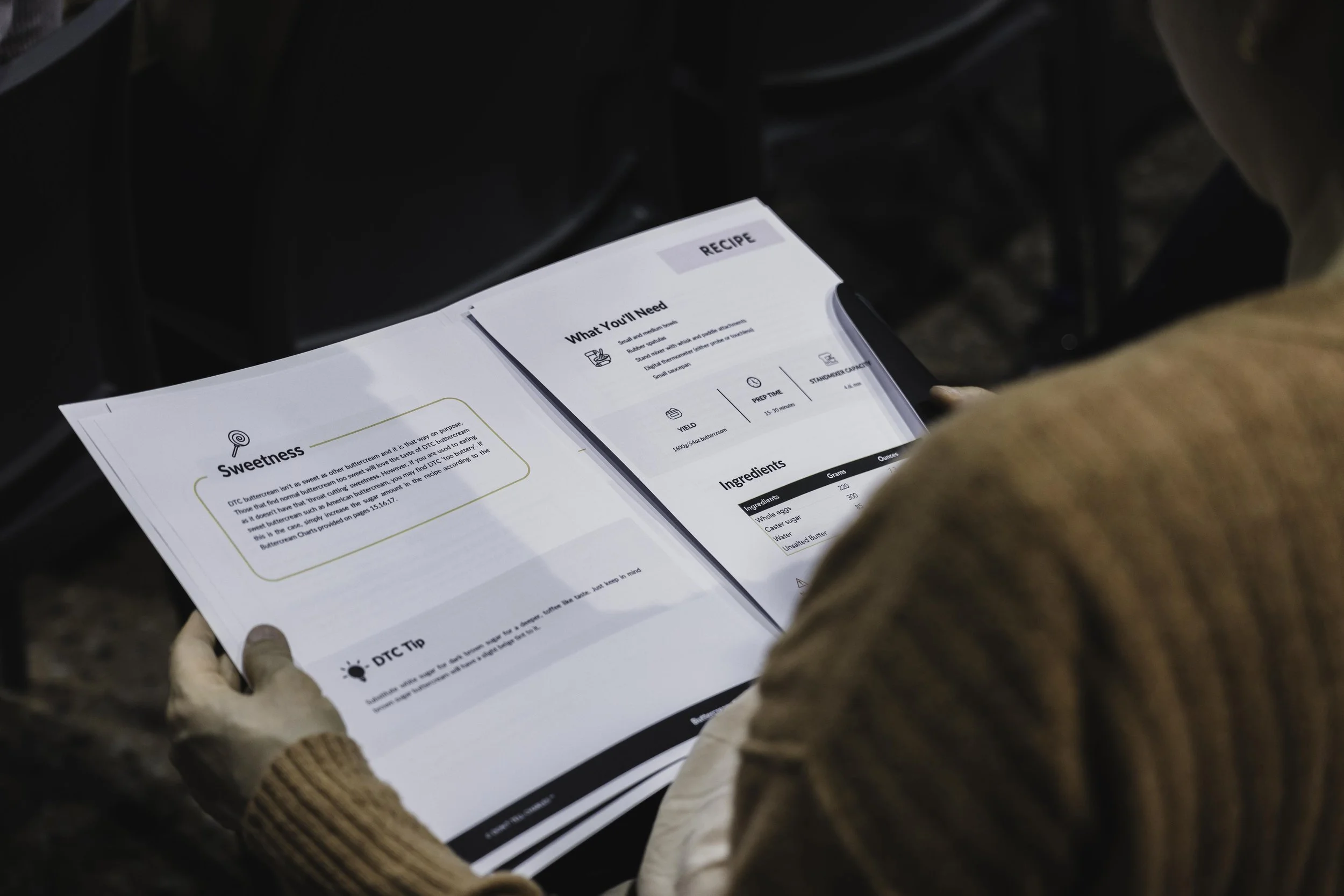 Person reading an open recipe book with sections on sweetness, ingredients, and tips.