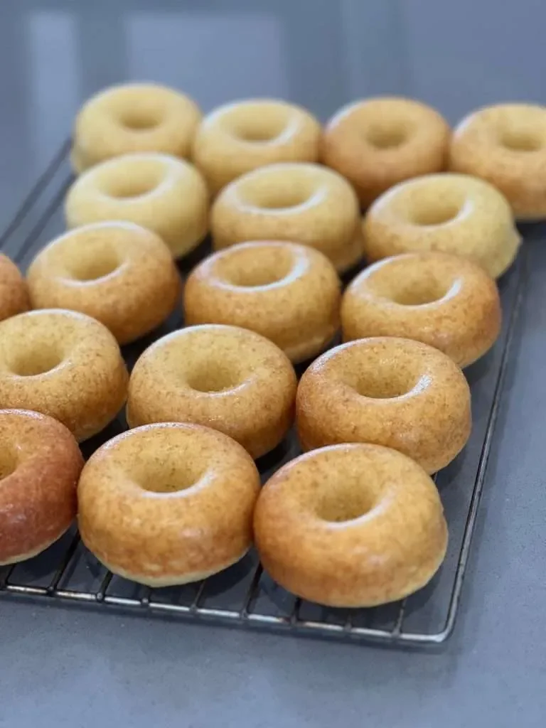 A tray of freshly baked mini bagels cooling on a wire rack.
