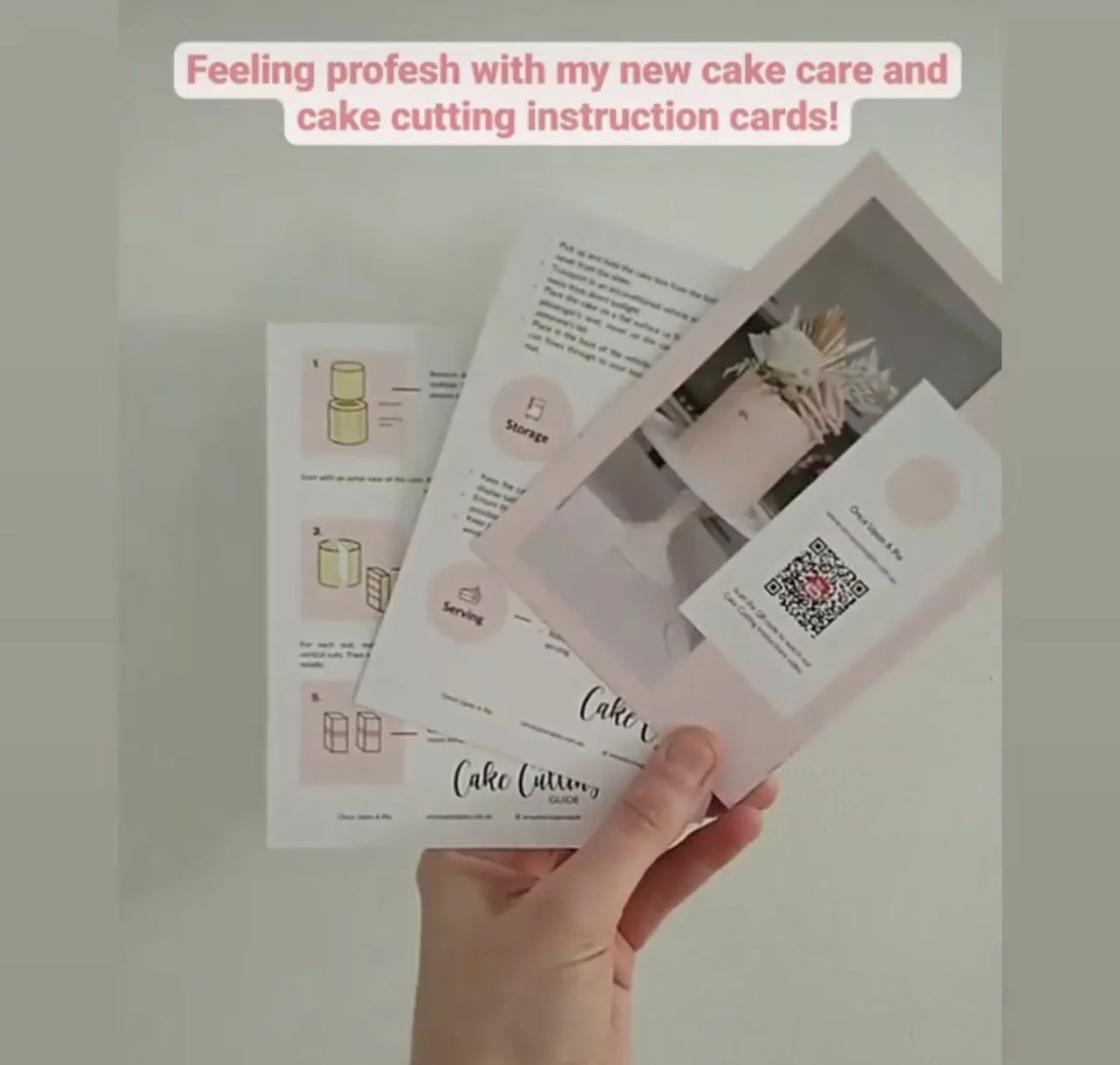 Person holding pink instructional cards for cake decorating, with related printed materials on a white surface.