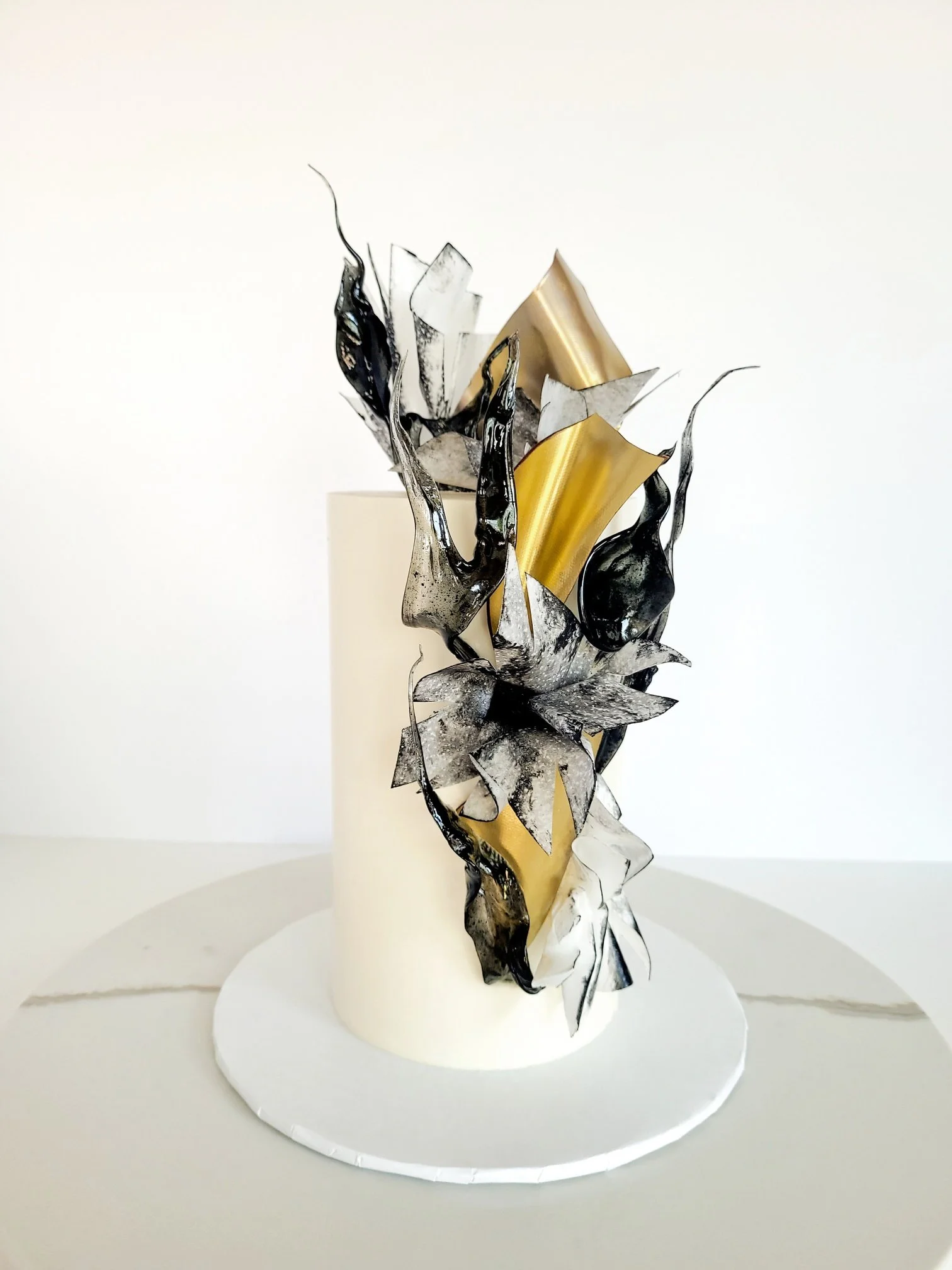 Modern sculptural cake with metallic and abstract design on a white base.