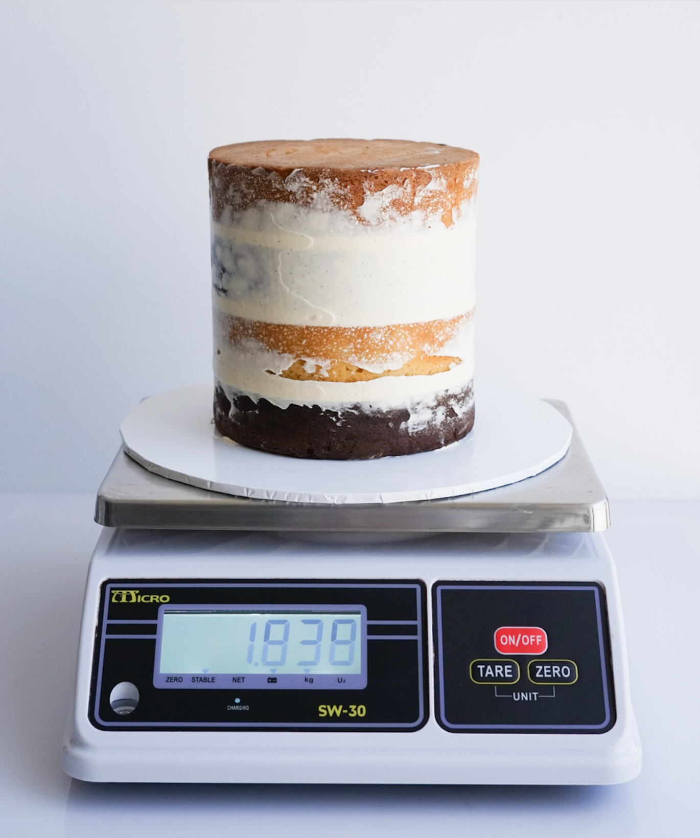 Cake filled with buttercream on a kitchen scale to record Weight B