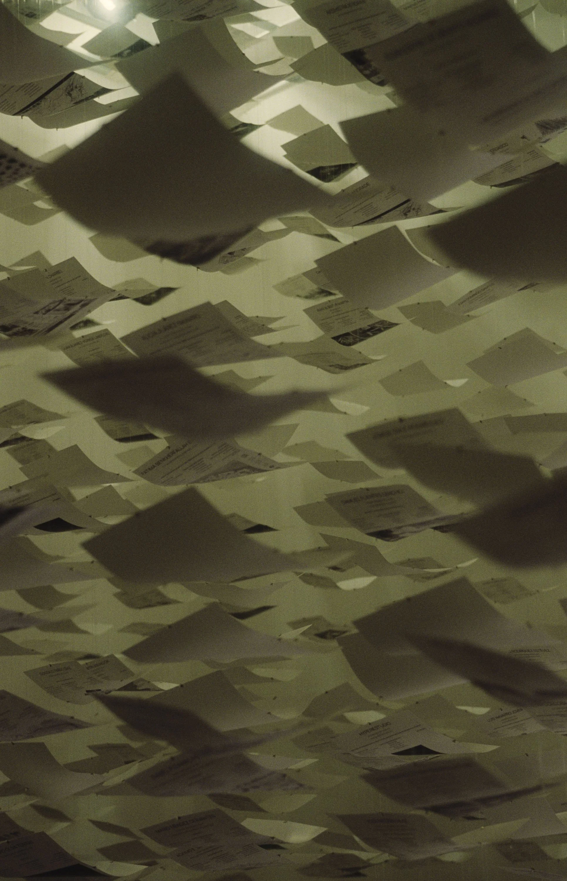 Ceiling with numerous white papers or documents hanging and casting shadows.