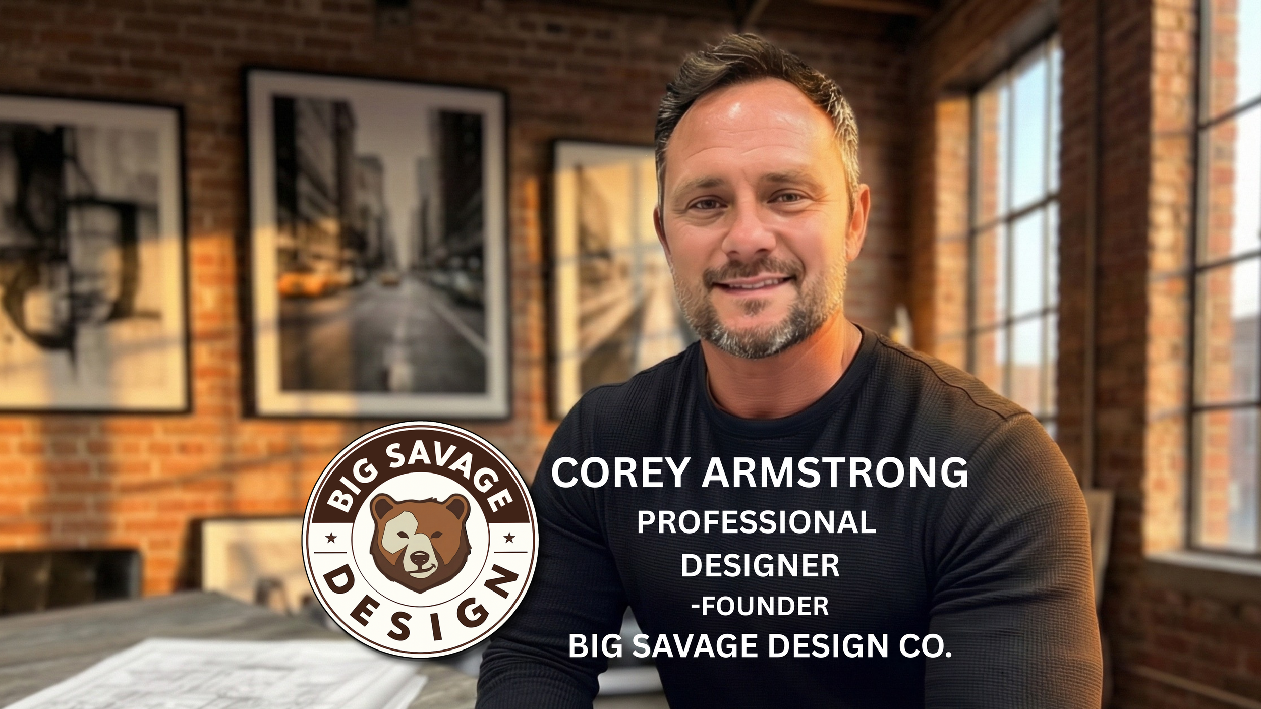 Photo of Corey Armstrong, a professional designer and founder of Big Savage Design Co., sitting at a table in a room with exposed brick walls and large windows. The background features framed black-and-white cityscape photographs. The logo of Big Savage Design, a bear's head, is overlayed on the image.