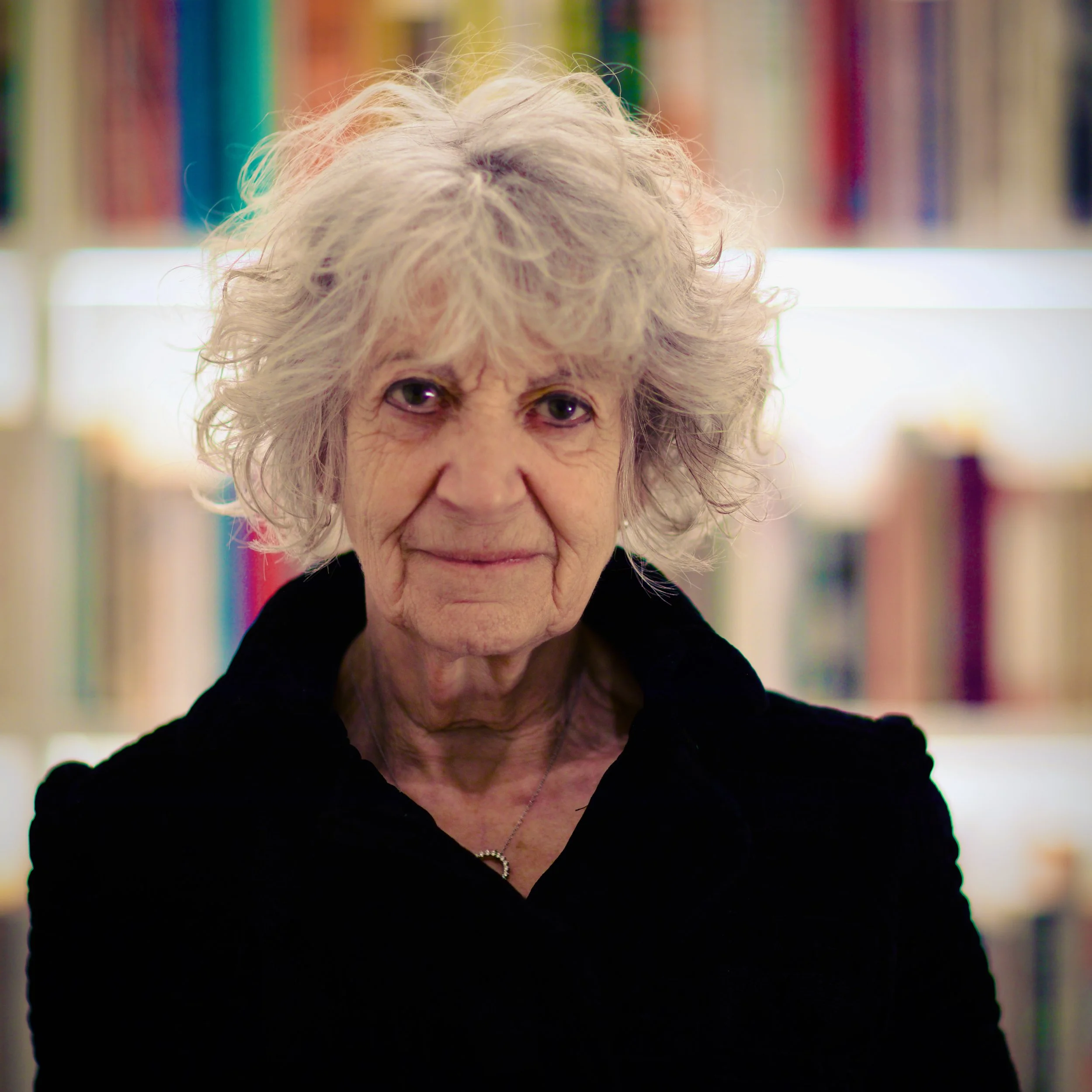 Portrait of Dr Susie Orbach in front of colourful bookshelves.