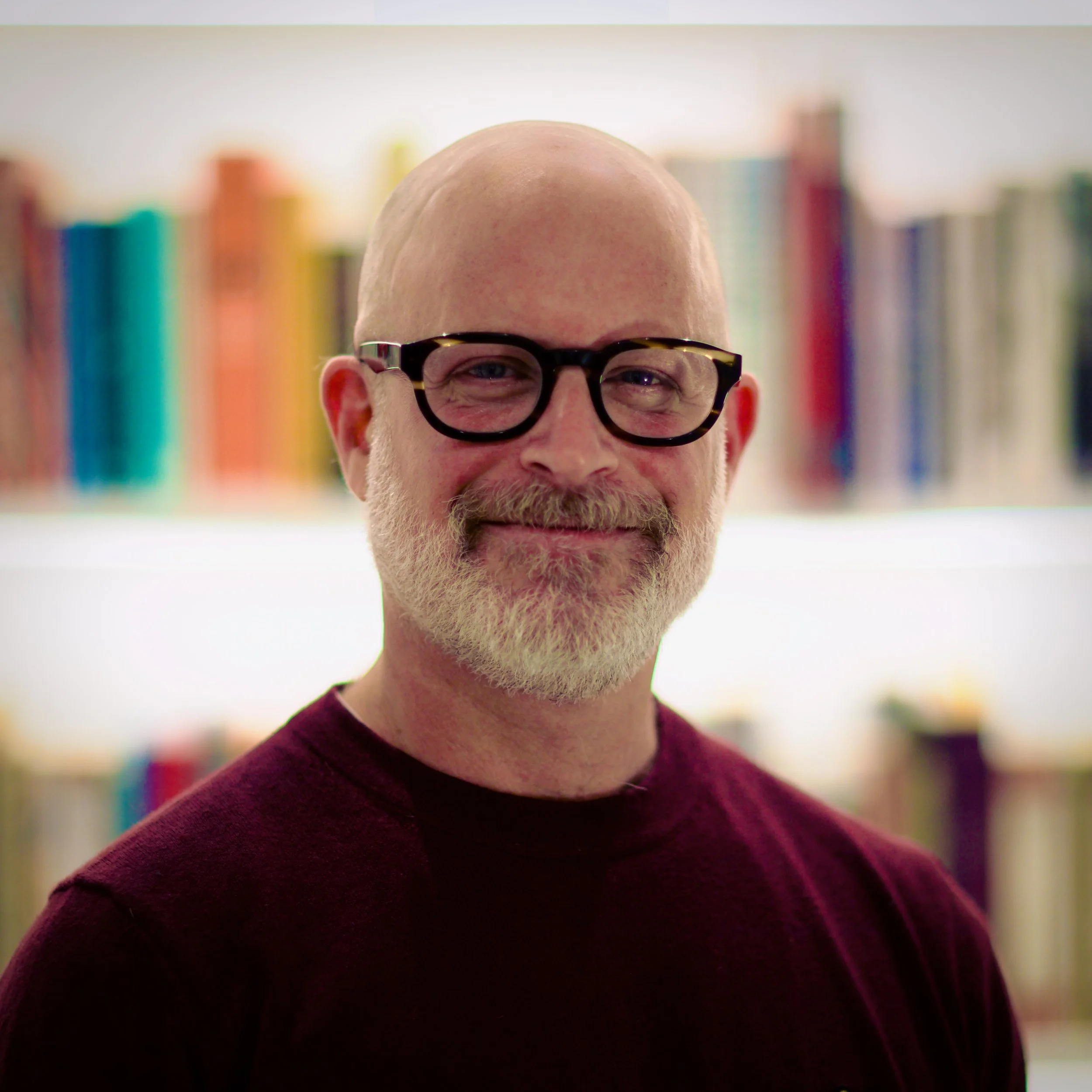Portrait of Dr Aaron Balick in front of colourful bookshelves.