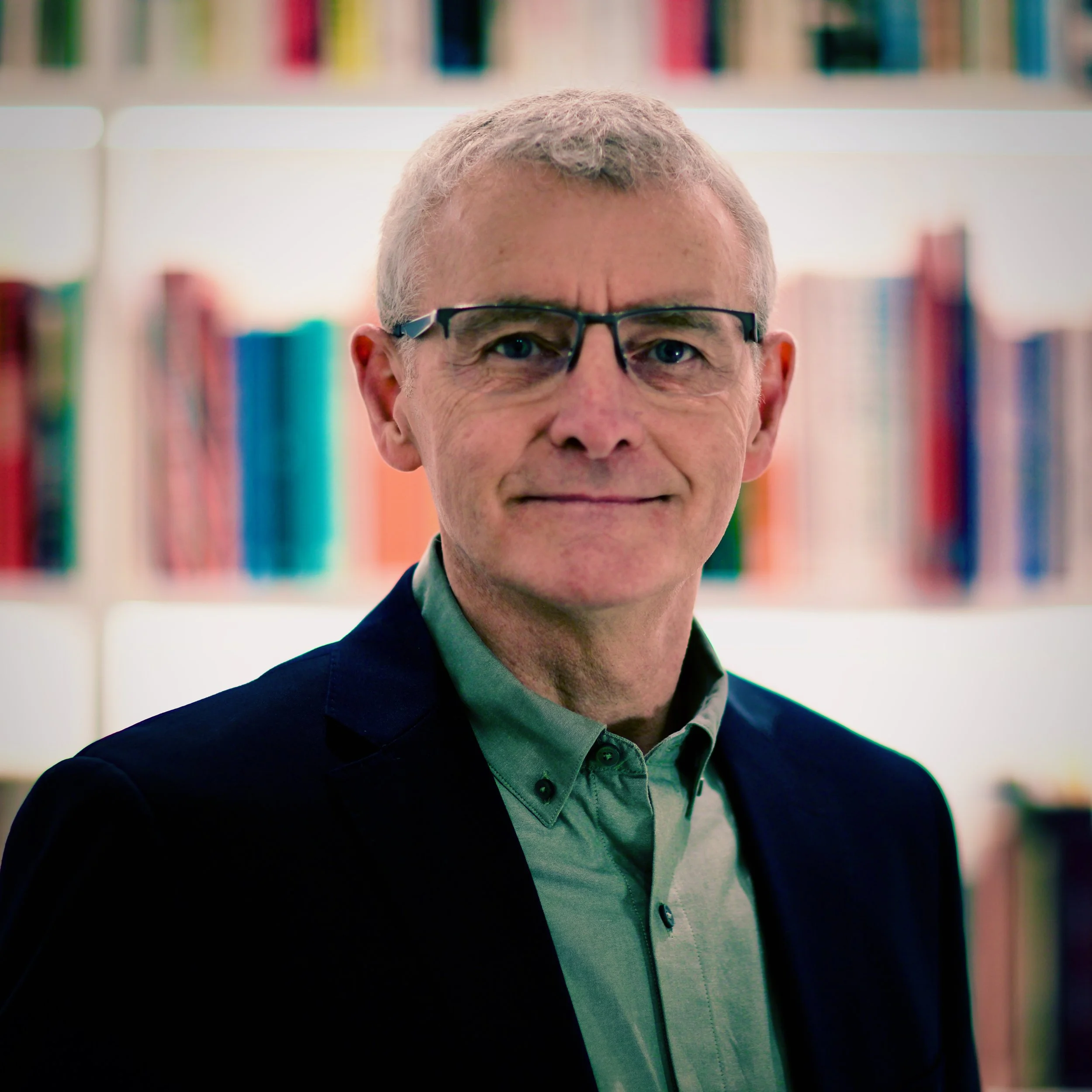Thomas Greally standing in front of a bookshelf.