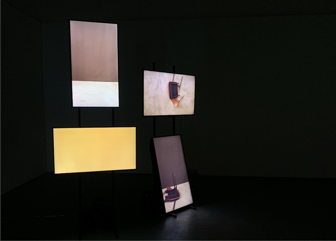 Installation of monitors on stands showing images of chairs falling