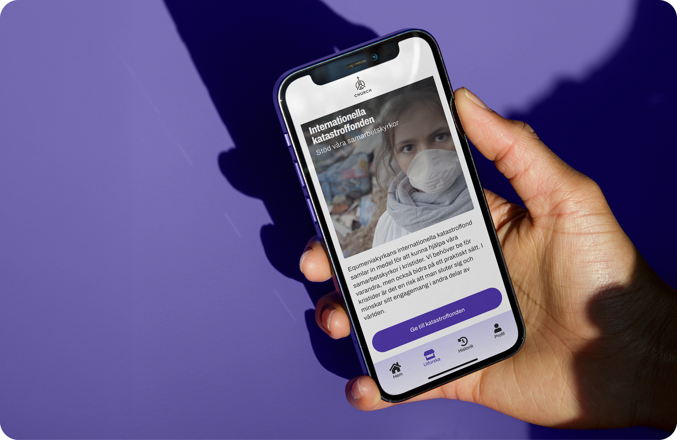 En person håller i en smartphone som visar information om Internationella katastroffonden på en skärm. Bakgrund i lila.