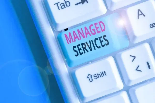 Close-up of a computer keyboard highlighting a key labeled "MANAGED SERVICES" with "MANAGED" in pink and "SERVICES" in black.