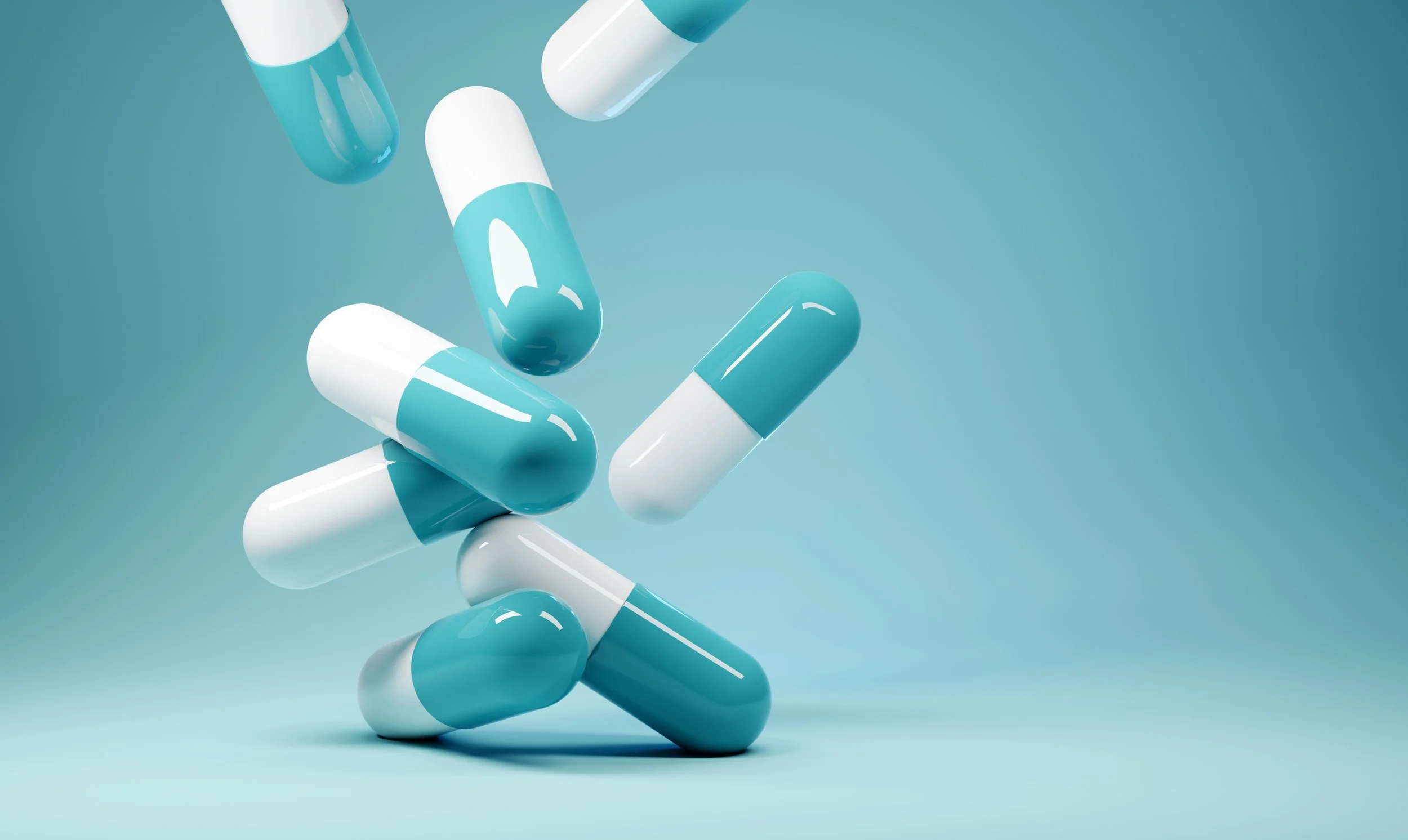 A collection of blue and white capsules floating against a light teal background.