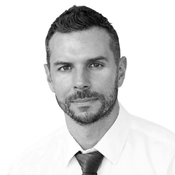Black and white portrait of a man with short dark hair, a beard, wearing a white shirt and dark tie.