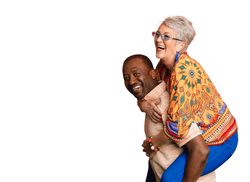 An elderly woman with grey hair and glasses, piggyback riding a smiling middle-aged man with dark skin, both dressed in colourful casual clothes.