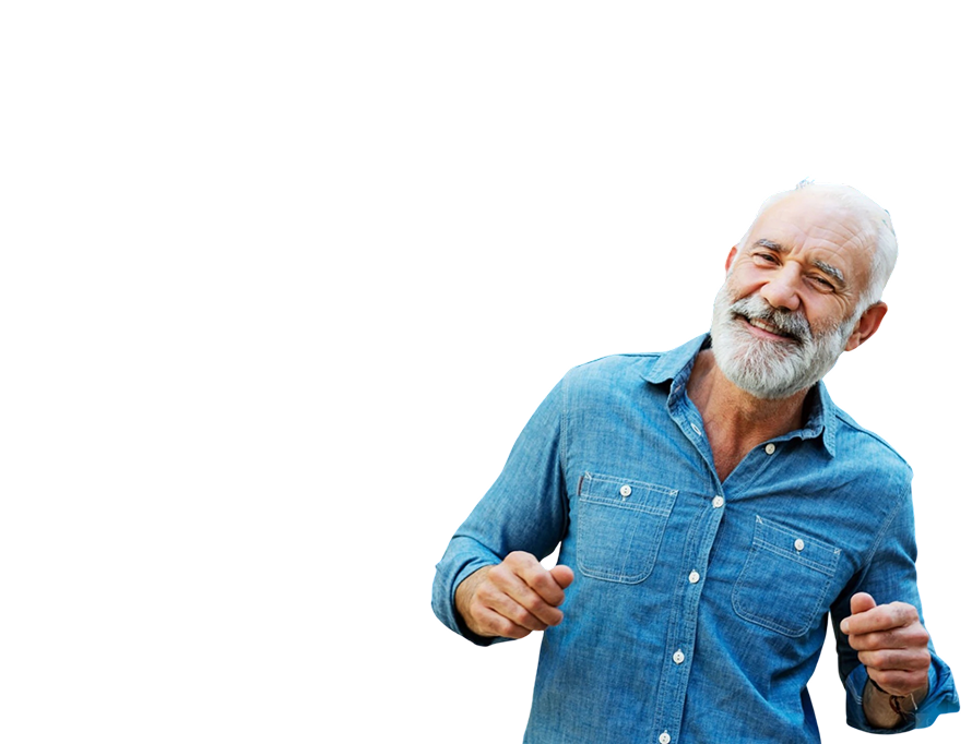 A happy elderly man with a white beard and gray hair, wearing a blue denim shirt, smiling with fists slightly clenched in a cheerful pose.