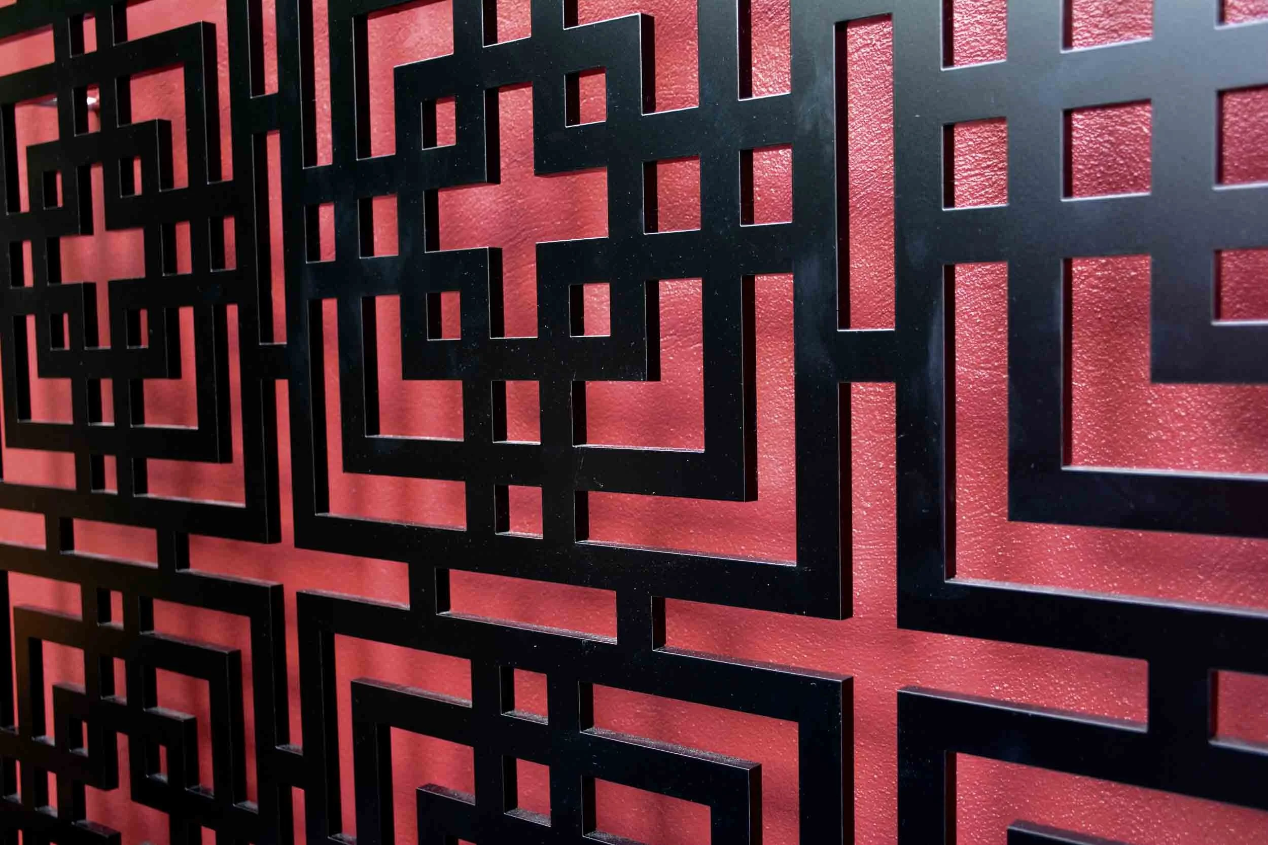 Close-up of black, geometric lattice pattern against a textured red background.