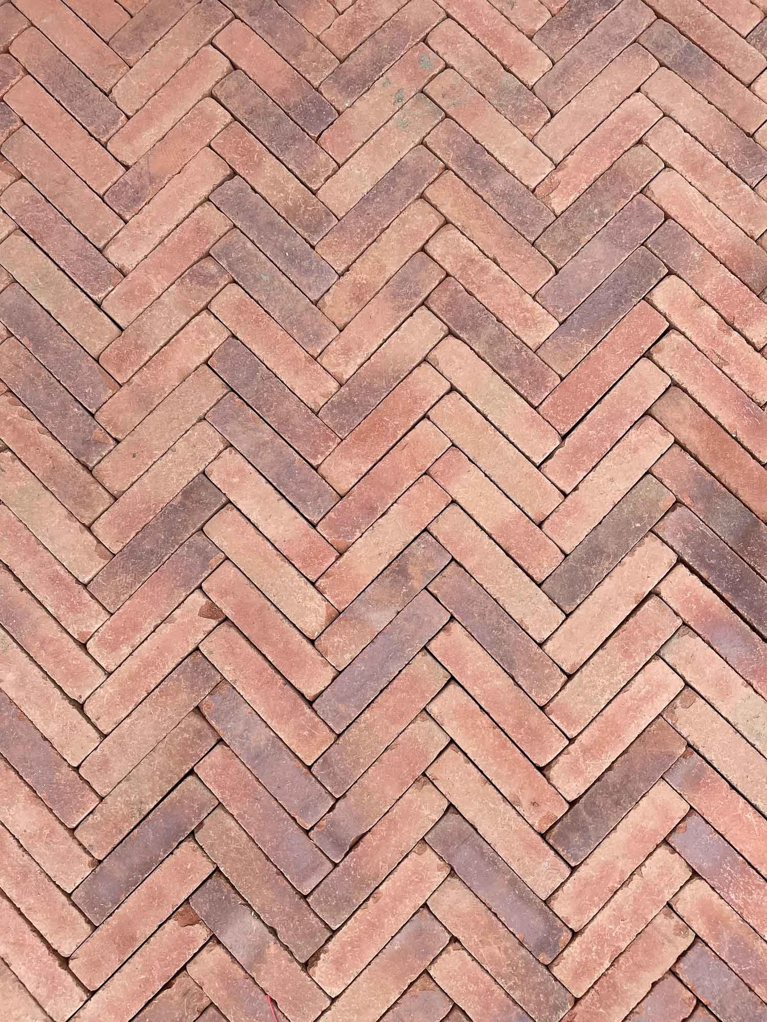 A close-up view of a red brick herringbone pattern floor.