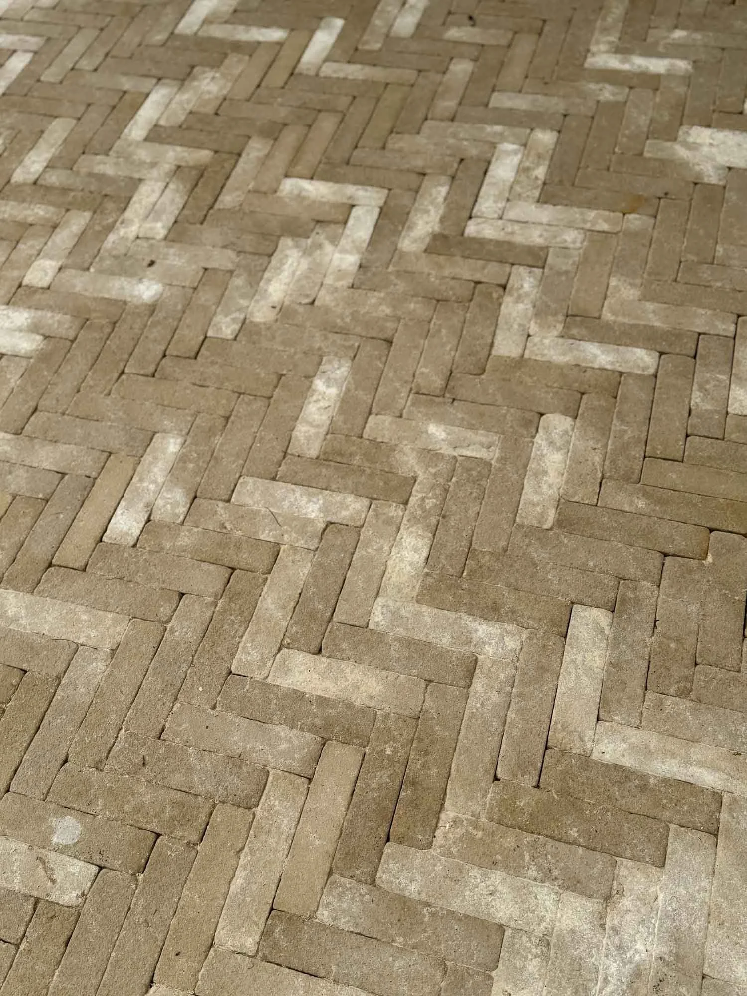 A close-up view of a tiled brick floor arranged in a herringbone pattern.