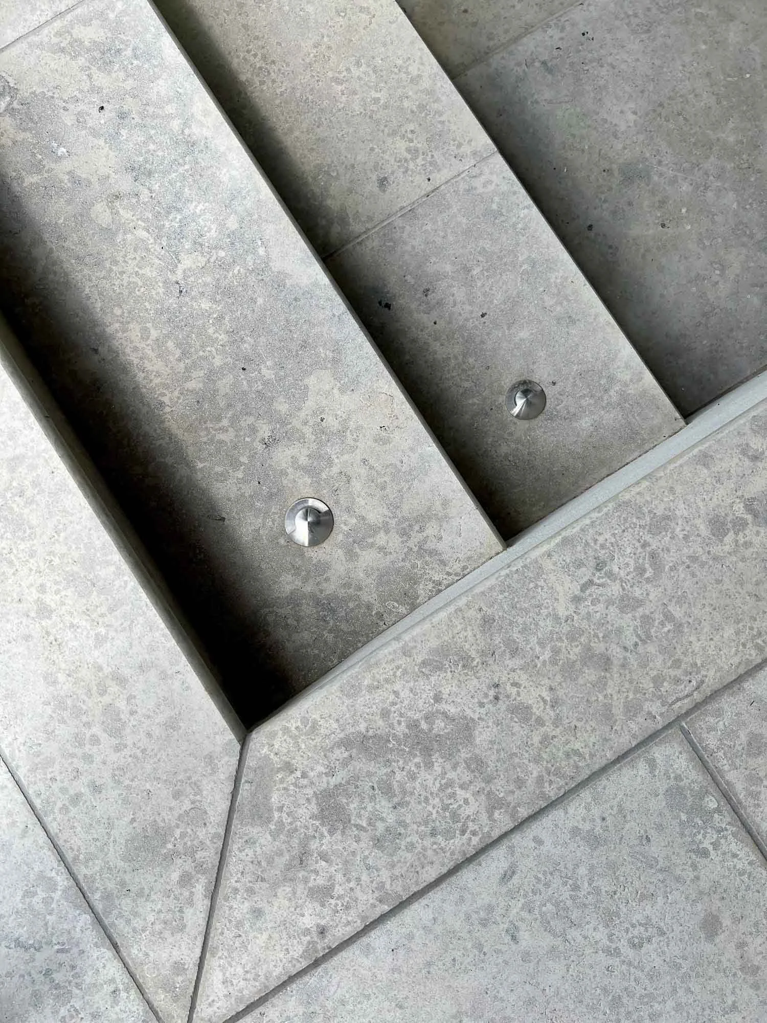 Concrete steps with metallic bolts and tiled flooring at the corner.