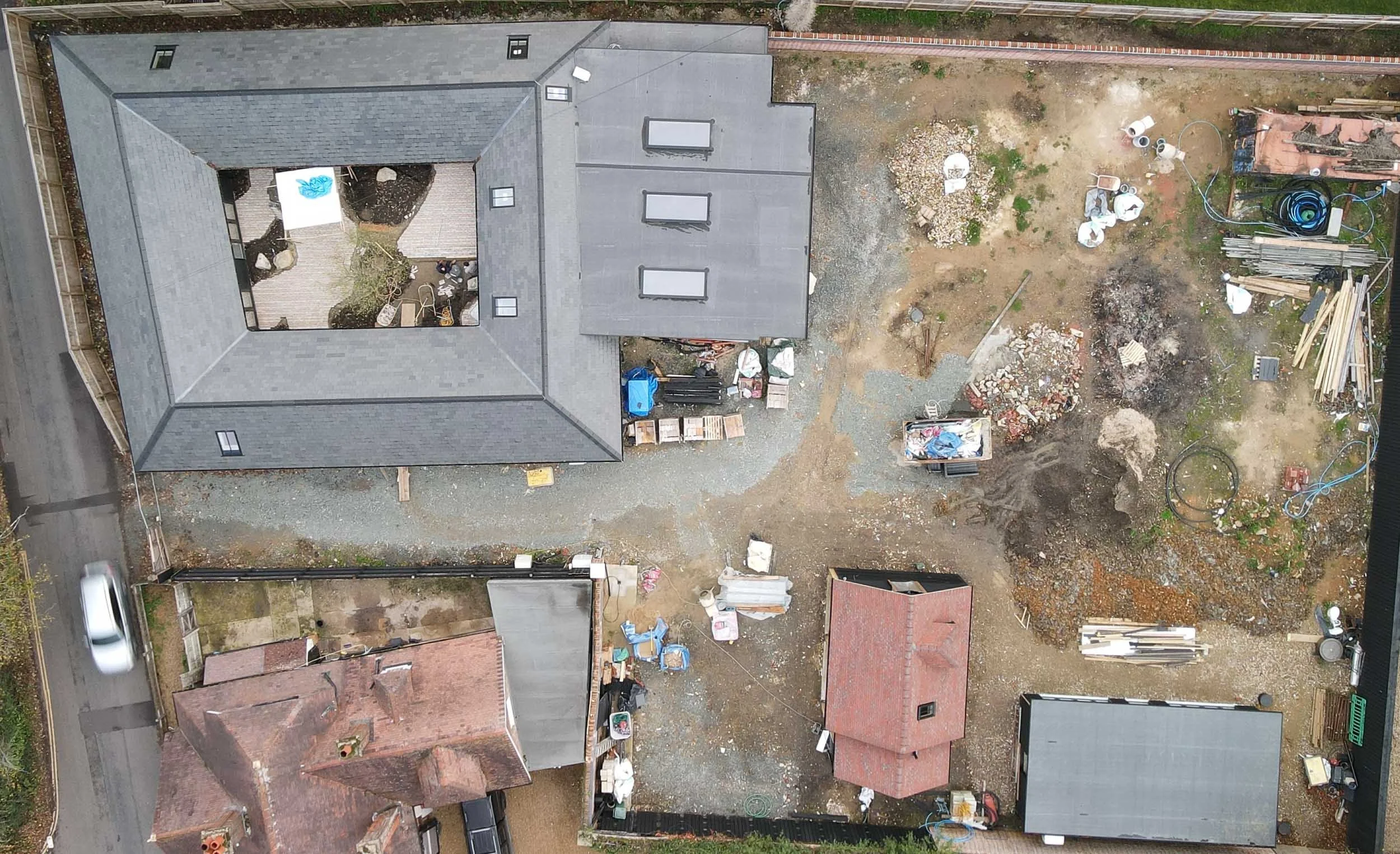Aerial drone photograph showing a garden construction site with a new house extension and various building materials