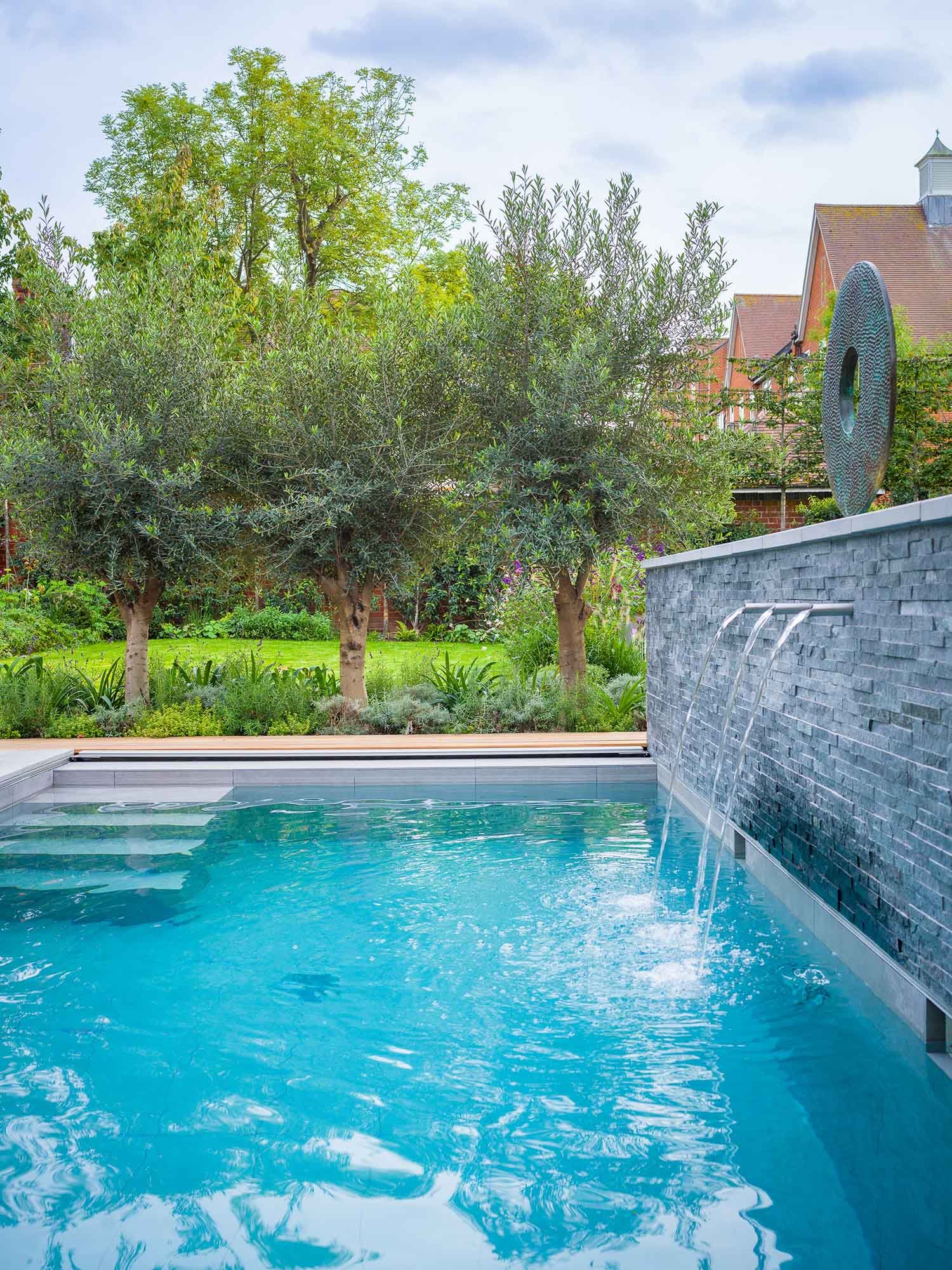 Garden view with curved lawn, shrubs, swimming pool and water feature