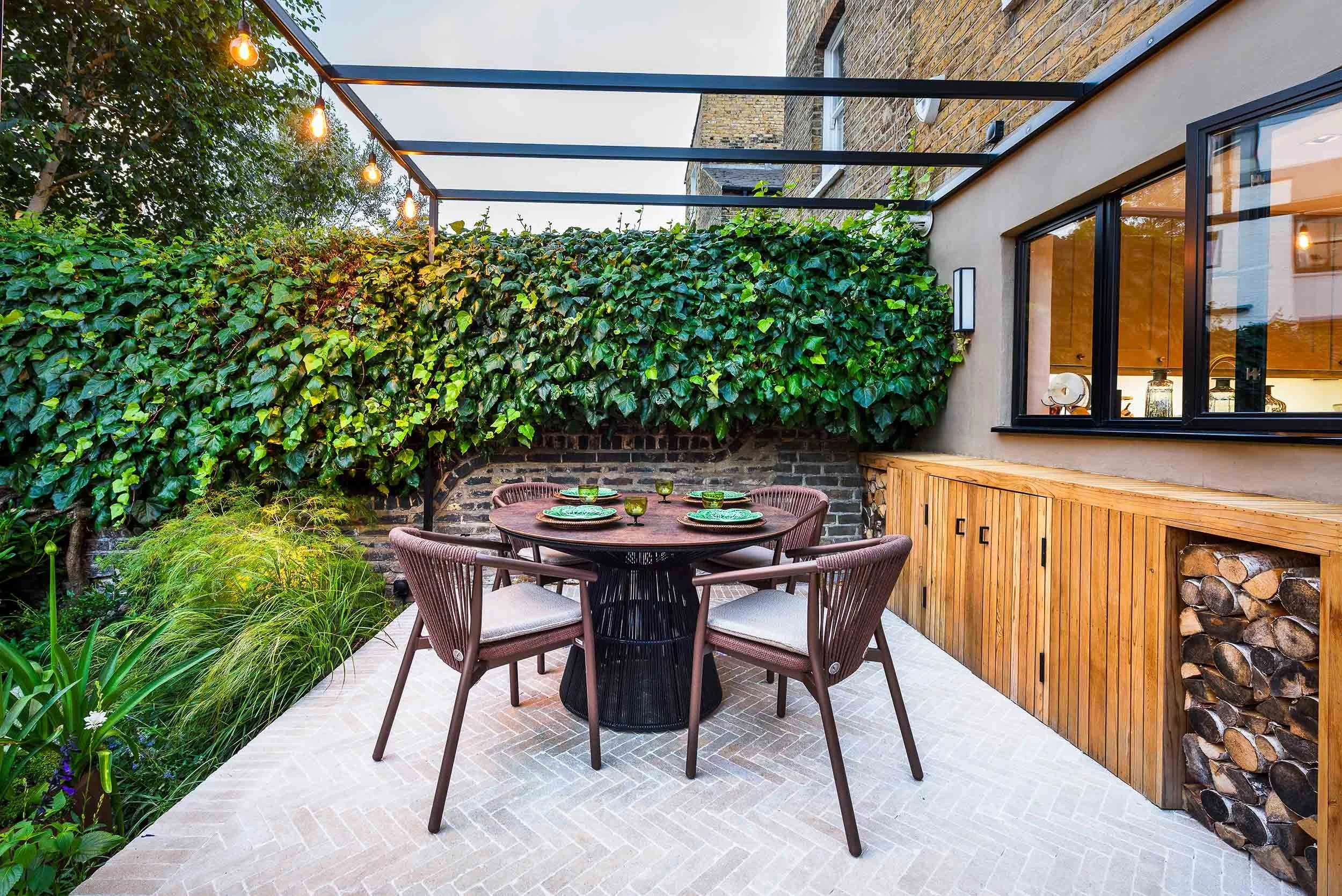 Contemporary dining area with a round table and brown chairs under a black metal pergola frame