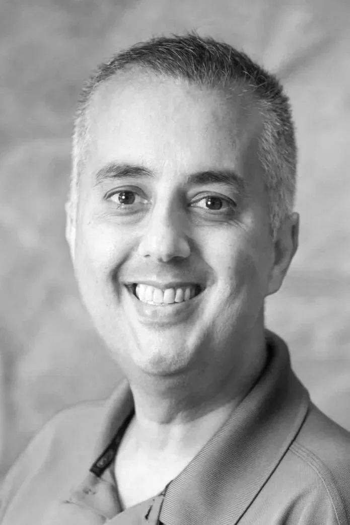 Black and white portrait of a smiling man with short hair wearing a collared shirt.