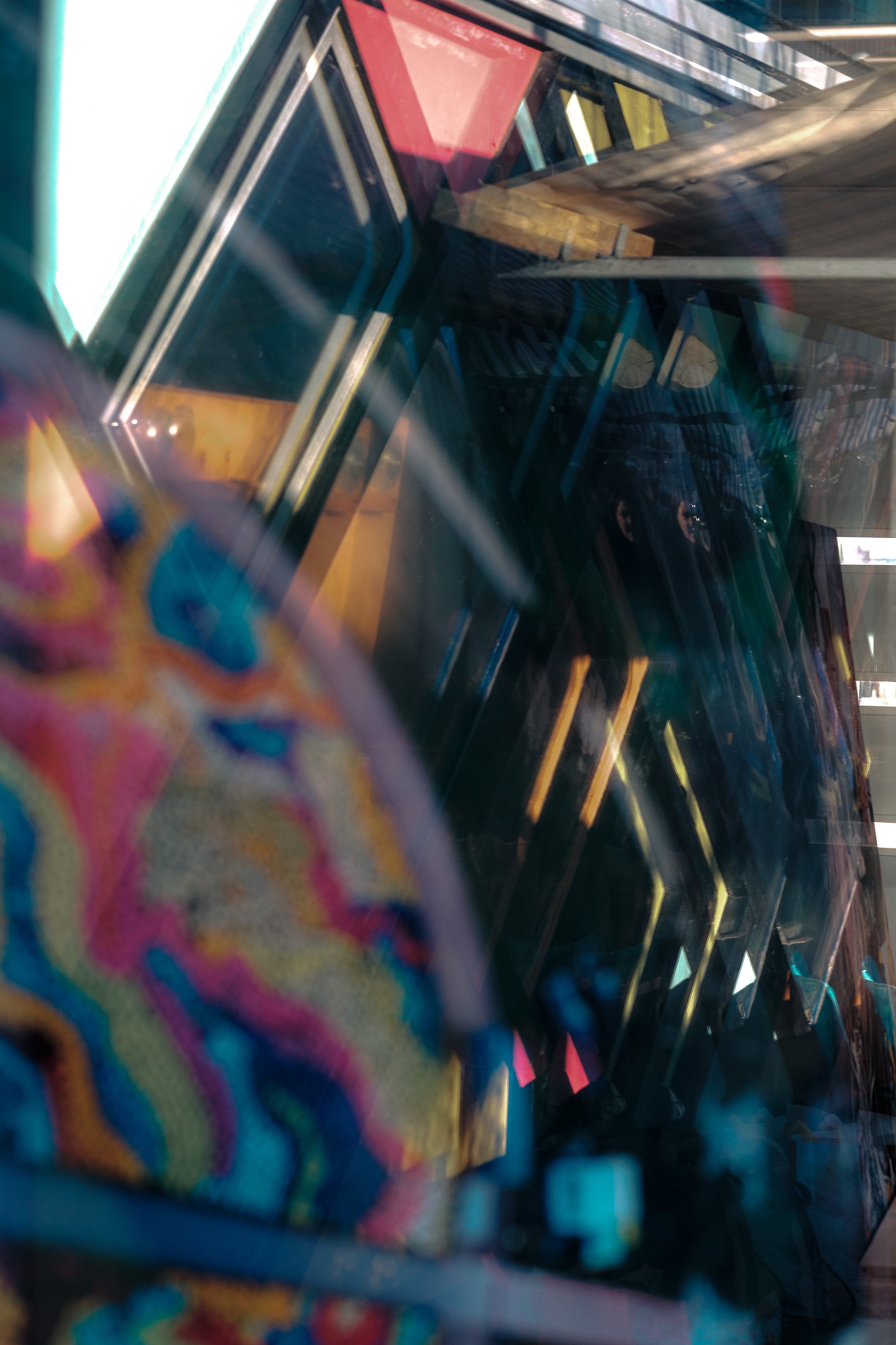 Colorful fabric or clothing item with abstract patterns, partially obscured by a reflective surface or glass.