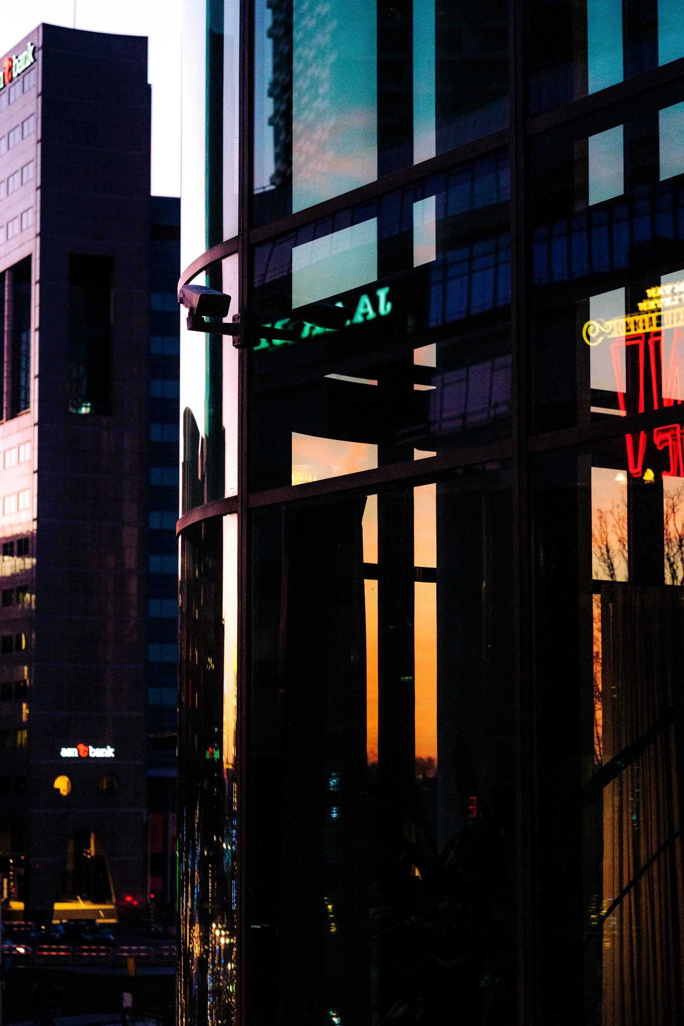 Reflection of a sunset sky with orange and purple hues in the glass windows of a modern office building in an urban setting