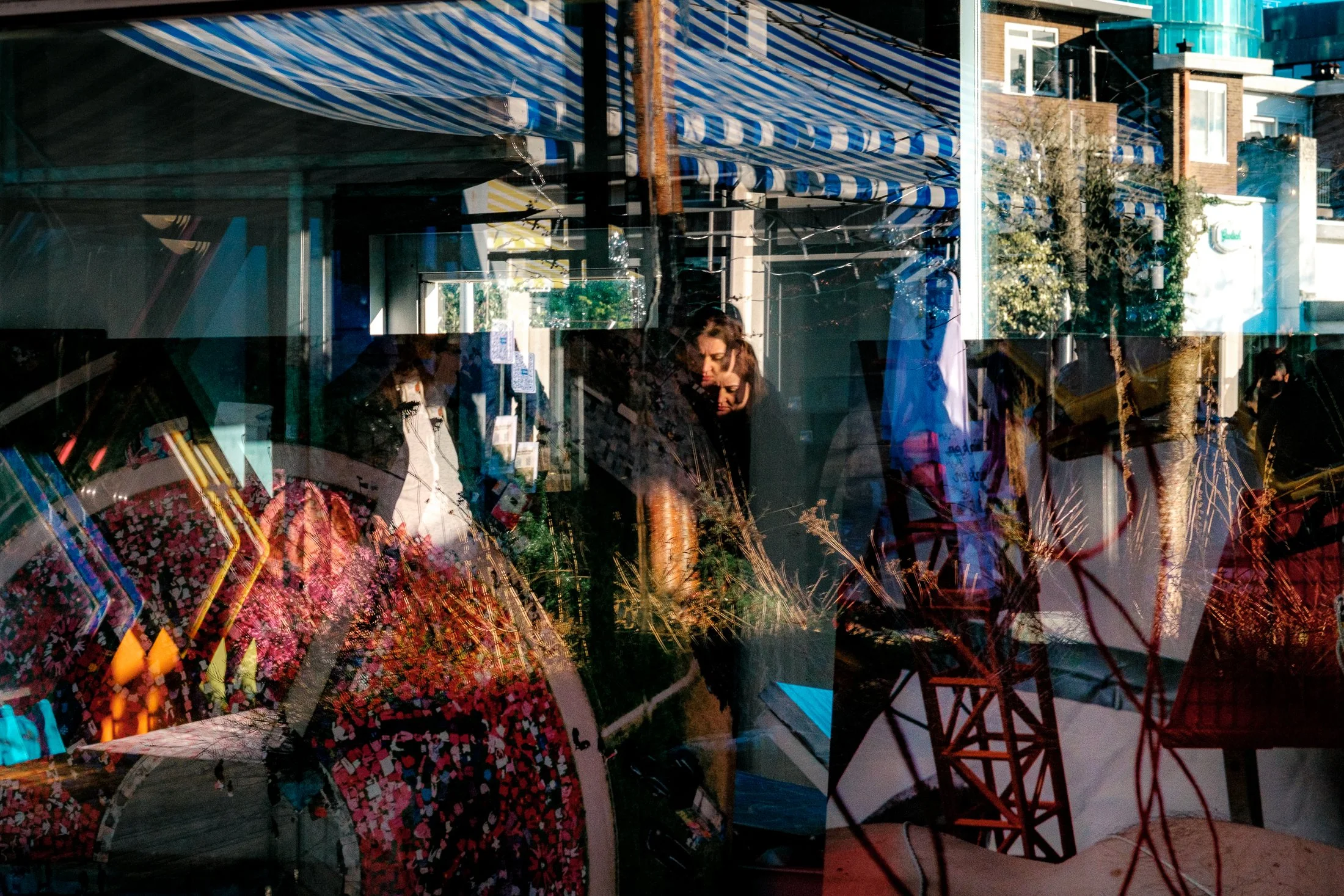 Reflected street scene with people walking past storefront in daytime