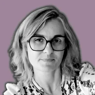 Portrait d'une femme blonde portant des lunettes avec un fond violet.