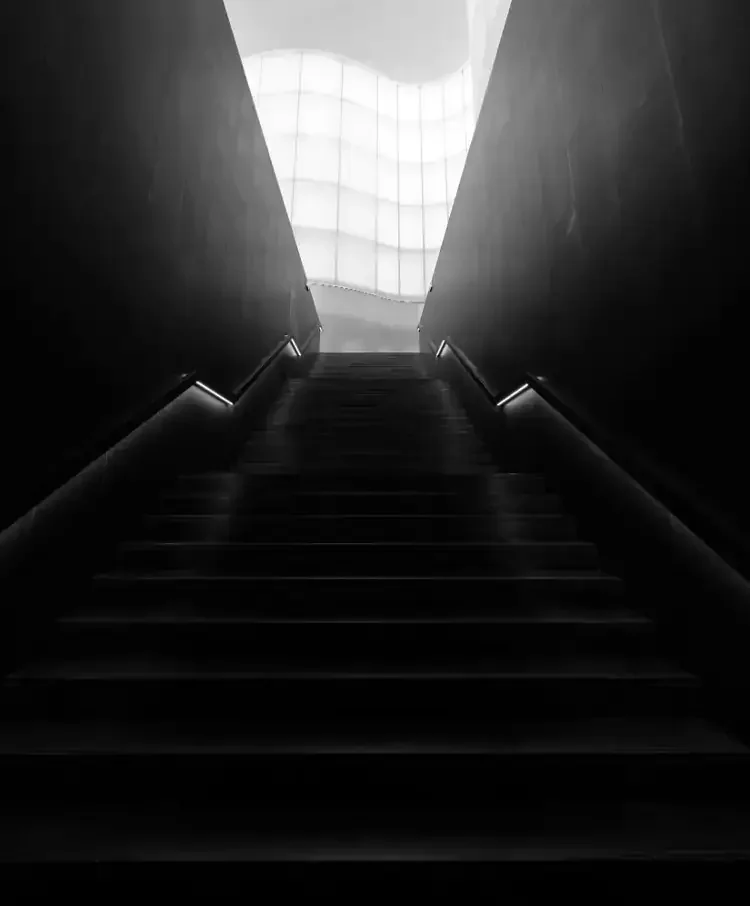 Escalier menant vers la lumière, symbolisant la formation en leadership et le développement de la posture managériale