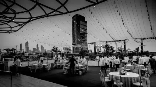 Réception professionnelle en extérieur sur un rooftop, avec tables dressées, personnel en service et éclairage suspendu