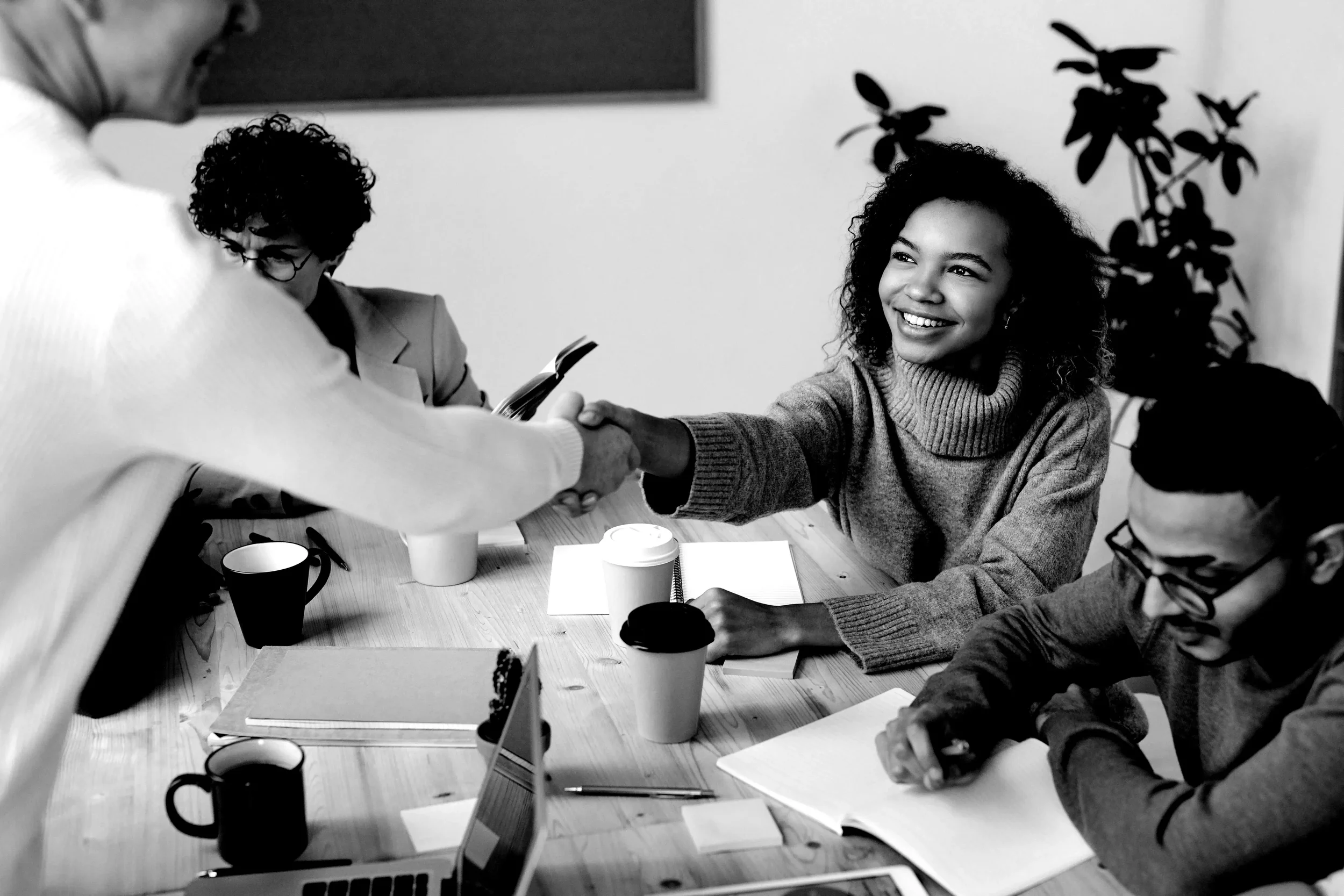 Une réunion de travail avec une jeune femme qui sert la main d'une personne de dos