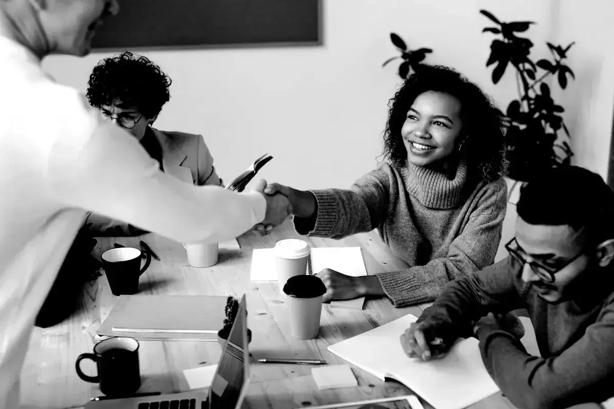 Une réunion de travail avec une jeune femme qui sert la main d'une personne de dos