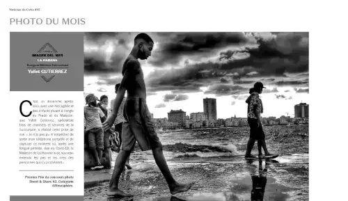 Une photographie en noir et blanc montrant deux enfants et un jeune adulte près de la mer à La Havane, Cuba. Un enfant marche sur une planche à roulettes devant un autre, et une autre personne, plus âgée, marche sur la roche, le ciel est nuageux.