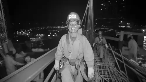 Ouvriers en train de travailler sur une grue de construction la nuit, portant des équipements de sécurité.