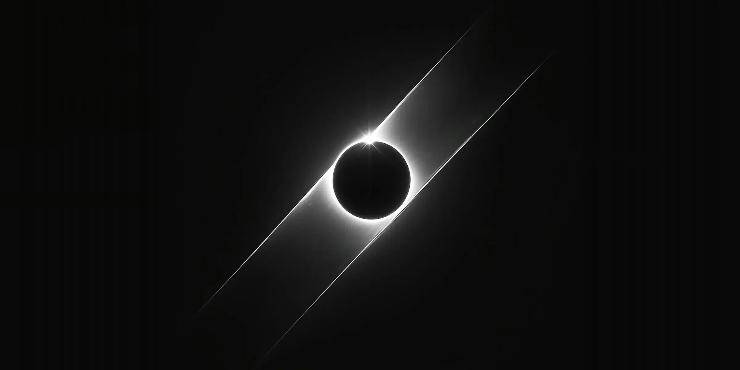 Une photo en noir et blanc représentant une éclipse solaire où la lune cache le soleil, créant une silhouette sombre avec un halo lumineux autour du cône lumineux.