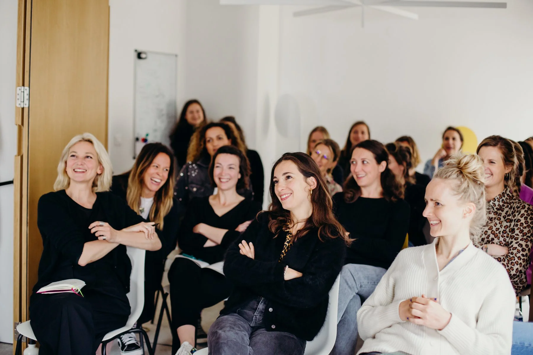 Groupe de femmes souriantes et riant lors d'une conférence ou d'un atelier en intérieur