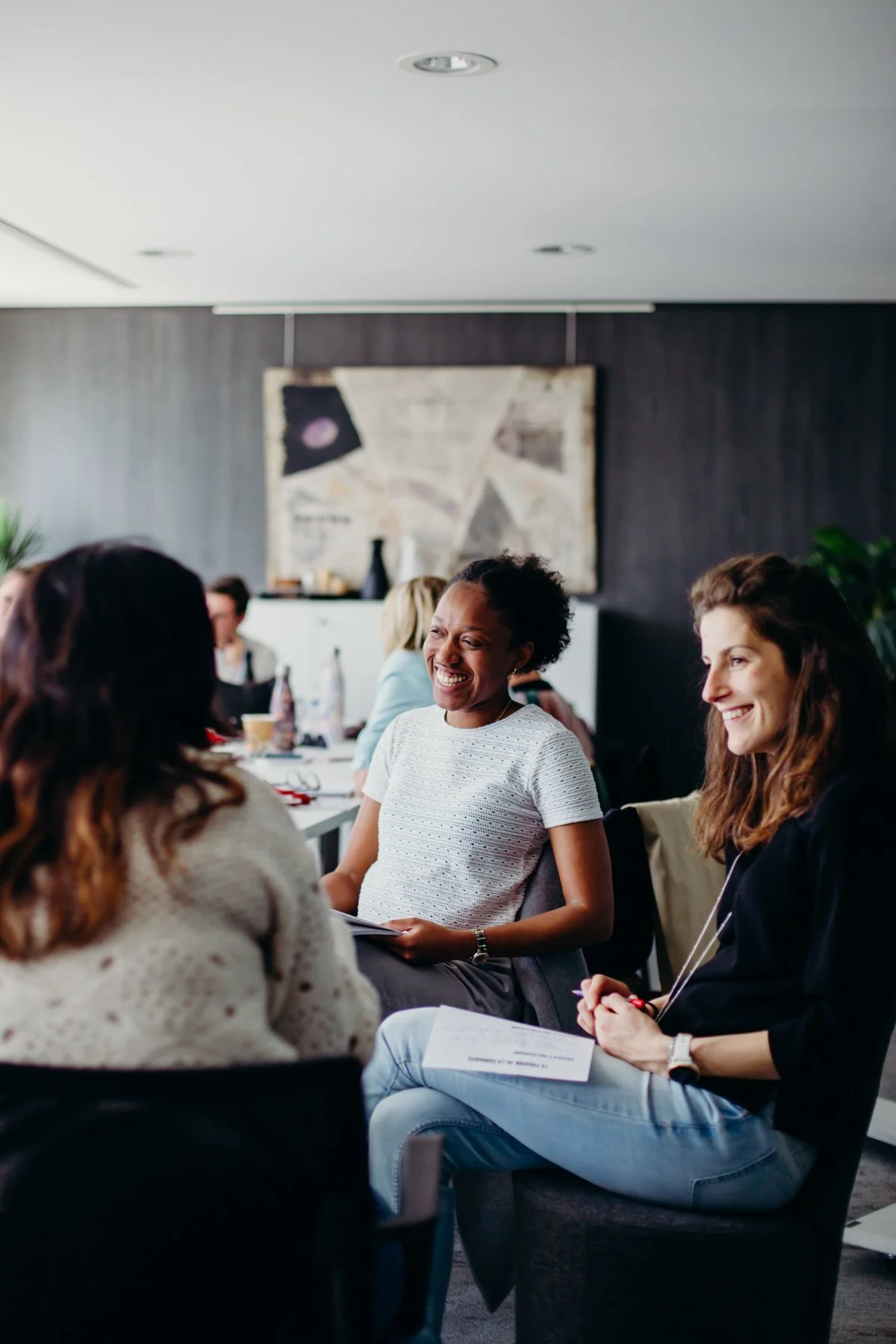 Un groupe de personnes souriantes en réunion dans une salle de conférence moderne.